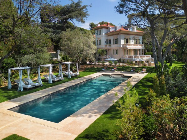 A swimming pool with lounge chairs and umbrellas, surrounded by well-maintained lawns and trees. - Grand-Hôtel du Cap-Ferrat, A Four Seasons Hotel (Saint-Jean-Cap-Ferrat)