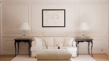 Une pièce avec un canapé blanc, deux tables d’appoint avec des lampes, une œuvre d’art encadrée et un vase décoratif.
