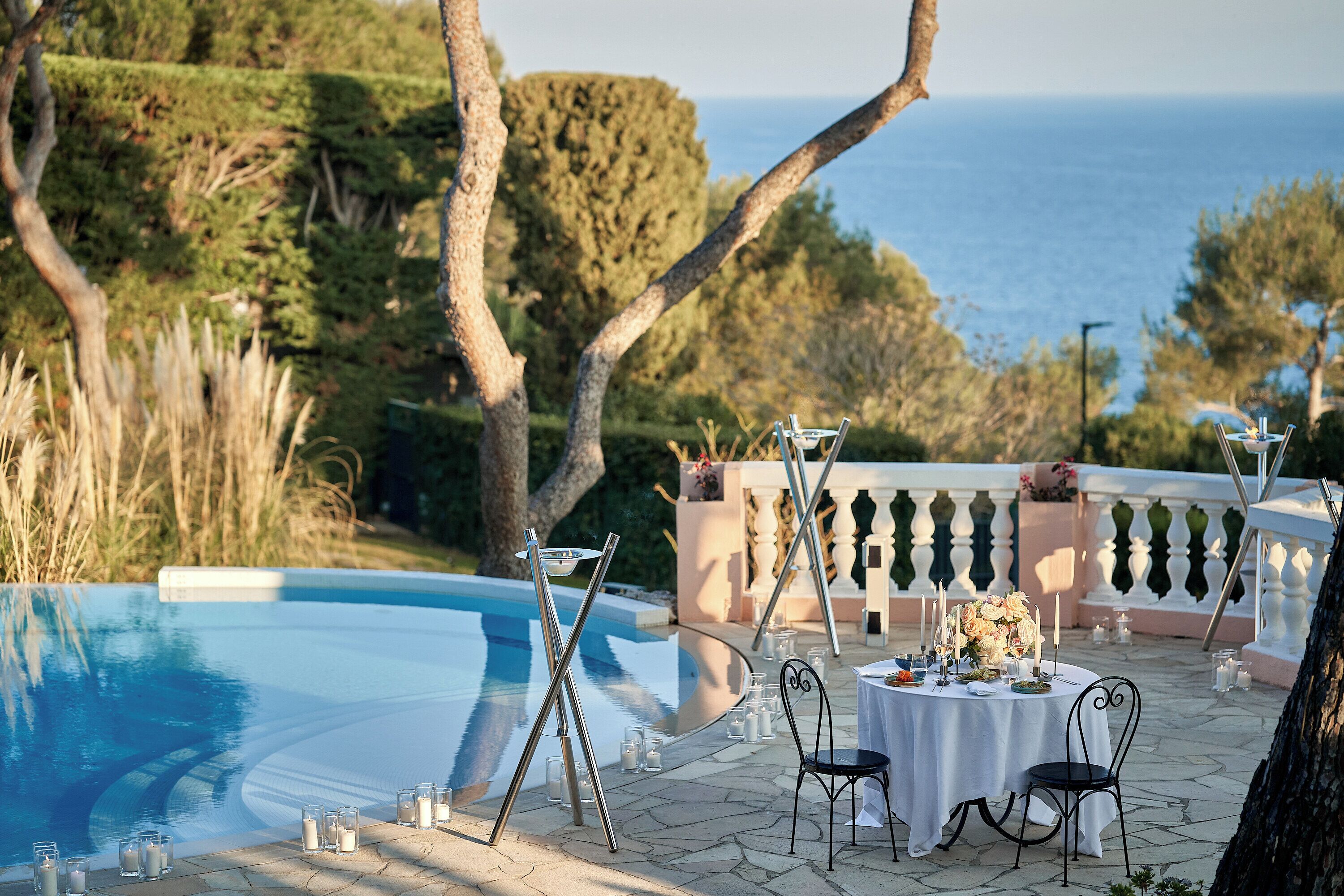 Un espacio de comedor al aire libre con piscina, sillas y una mesa dispuesta para una comida.