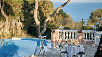 Un espacio de comedor al aire libre con piscina, sillas y una mesa dispuesta para una comida.