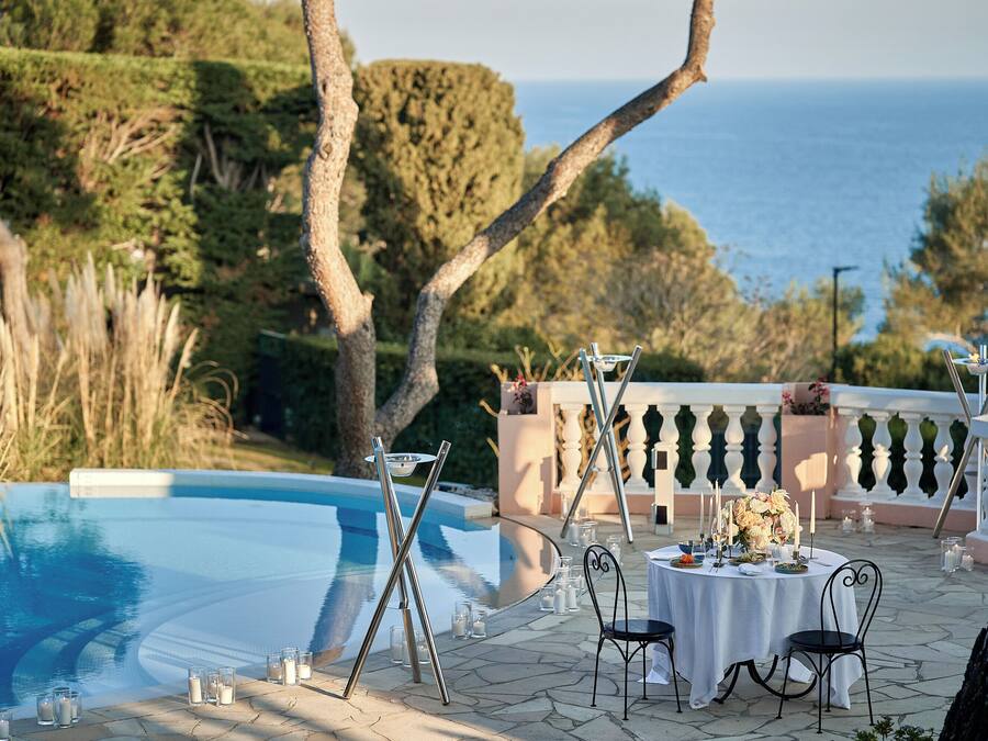 Un espacio de comedor al aire libre con piscina, sillas y una mesa dispuesta para una comida.