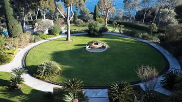 A circular garden with a central fountain, surrounded by a well-maintained lawn and various trees.