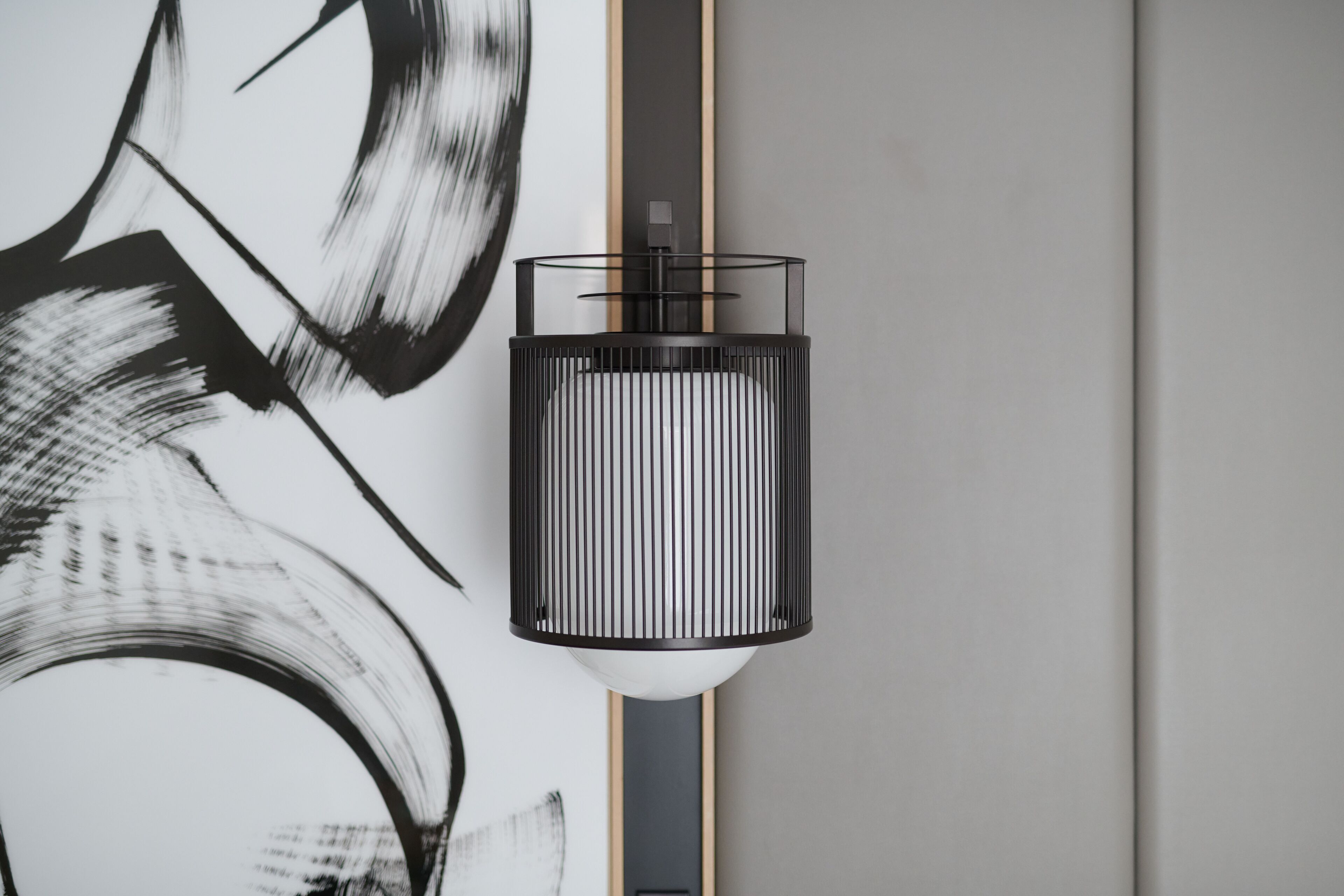 Un interior modern amb un disseny minimalista, que destaca per una làmpada de paret i un quadre abstracte gran.