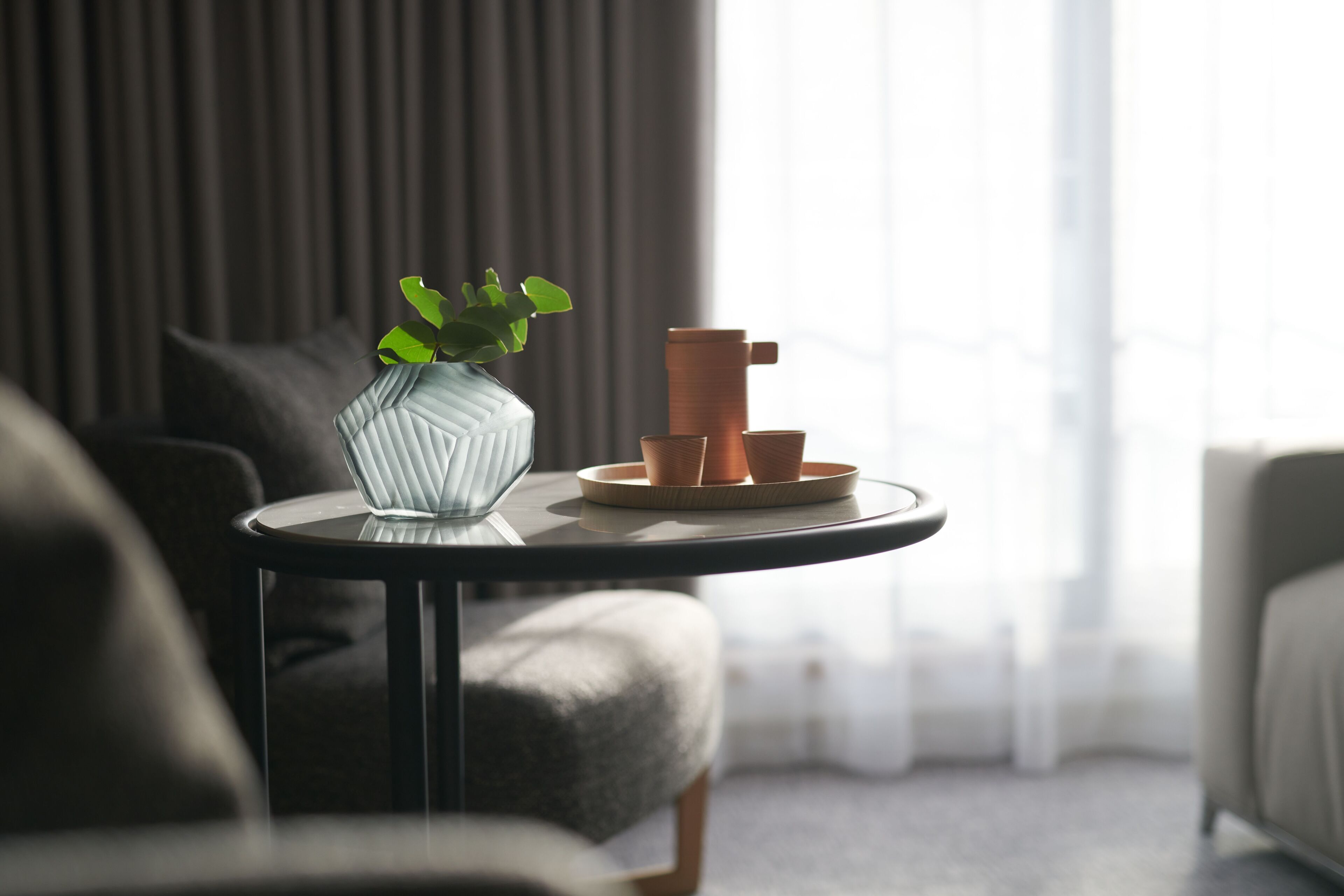 Un salon moderne avec une table ronde, un vase contenant une plante et des pots en terre cuite.