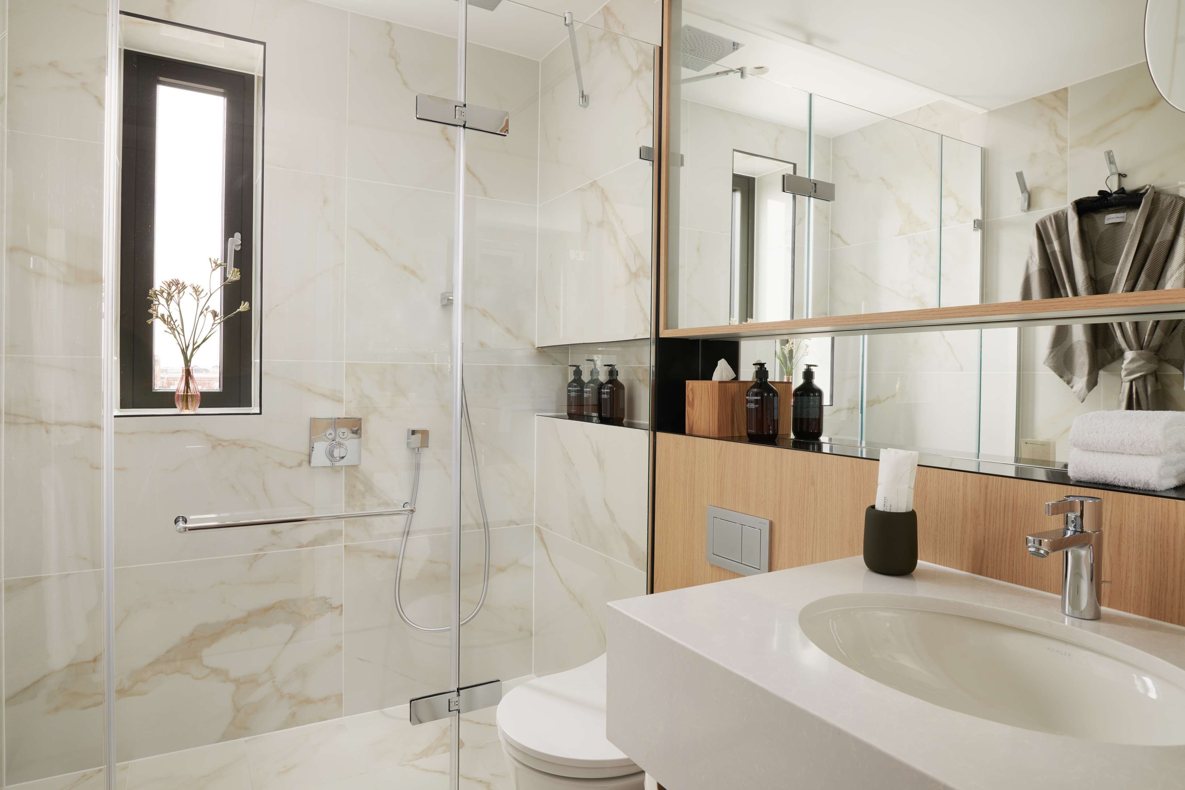 A modern bathroom with a glass shower enclosure, a white sink, and a large mirror.