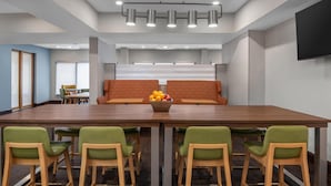 A modern conference room with a long table, green upholstered chairs, a sofa, and a fruit bowl. - Hampton Inn Memphis/Southaven (Southaven)