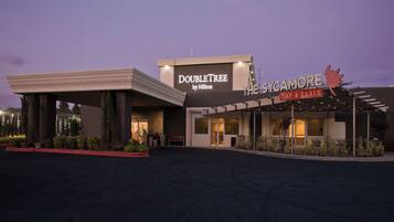 L’entrée d’un hôtel, dotée d’un espace abrité et d’une enseigne indiquant « DoubleTree by Hilton » et « The Sycamore Tap & Table ».