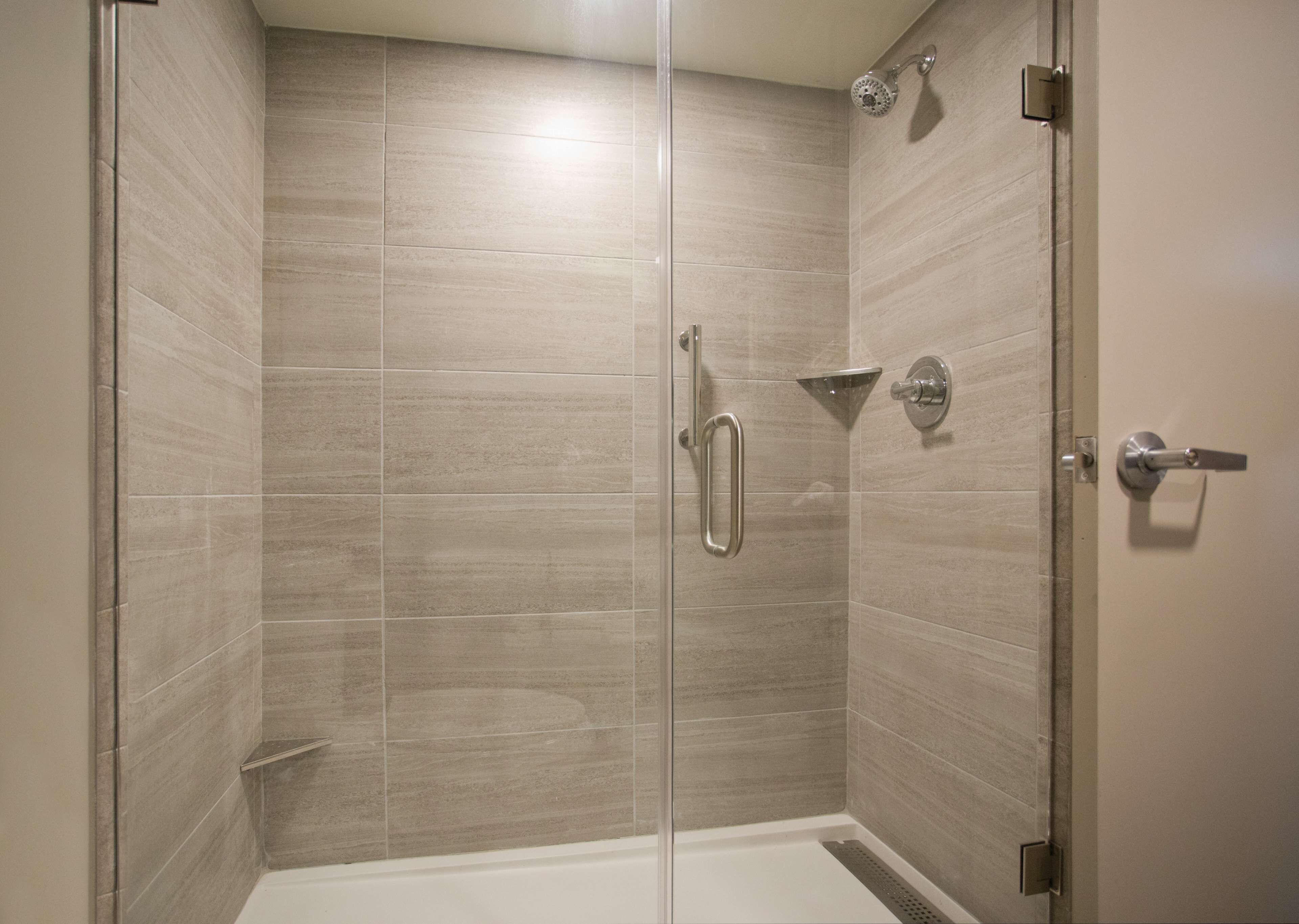 A walk-in shower with a glass door, tiled walls, and a showerhead.