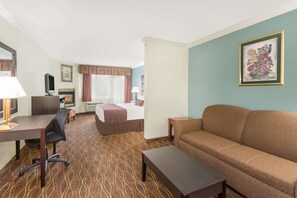 A hotel room with a bed, a sofa, a desk, and a TV. - Baymont by Wyndham Helen (Helen)