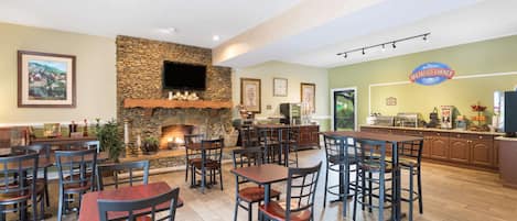 A restaurant with a stone fireplace, multiple dining tables and chairs, and a breakfast counter.