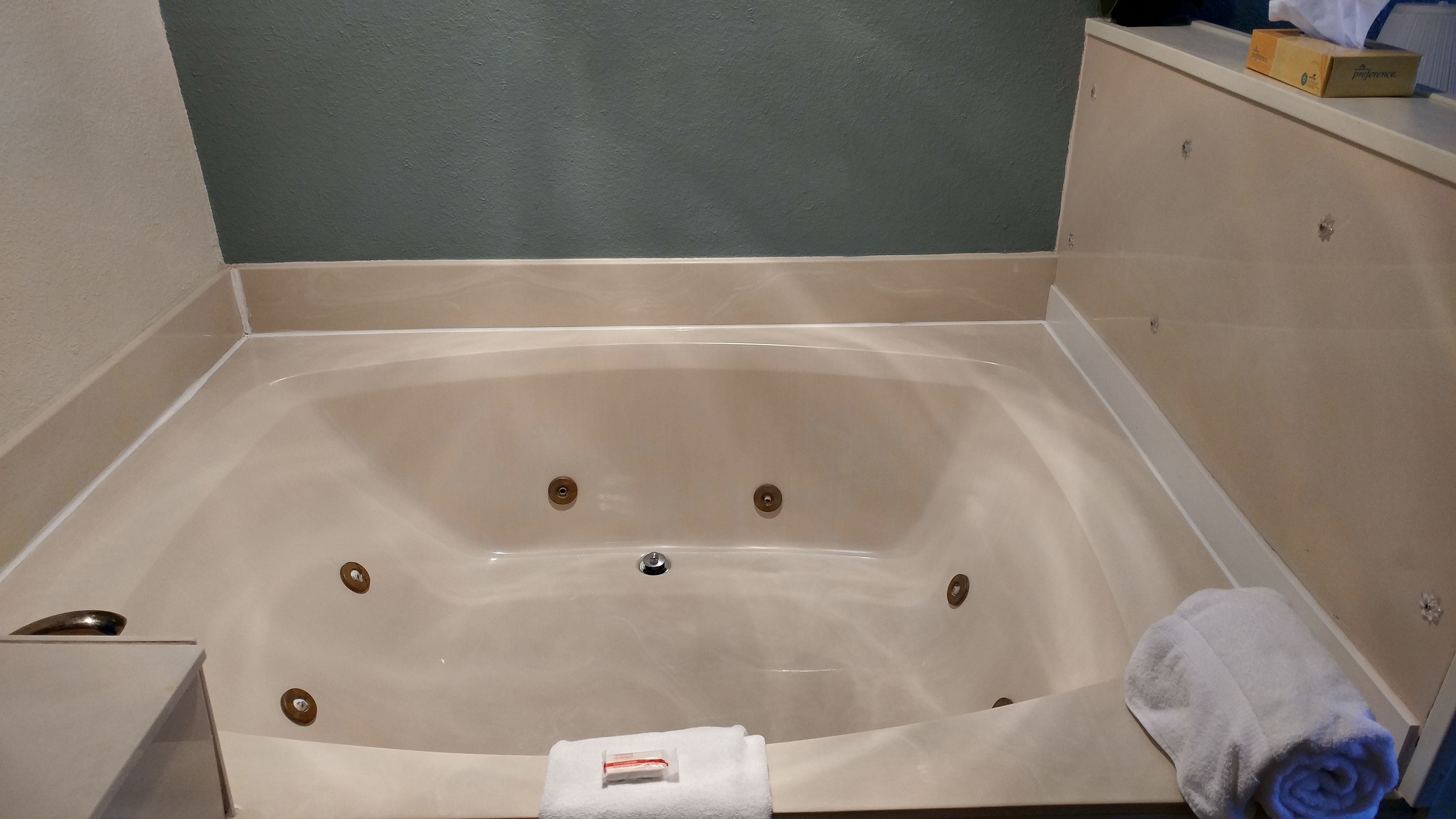 A bathtub with a white towel and a bottle of lotion.