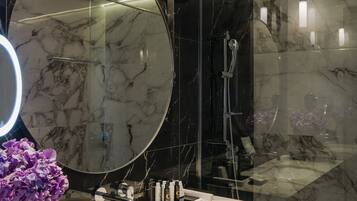 Une salle de bain moderne avec un grand miroir, un lavabo en marbre et une douche à parois de verre.