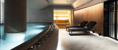 Un área de spa con un jacuzzi, sillones de descanso y una pared de madera.