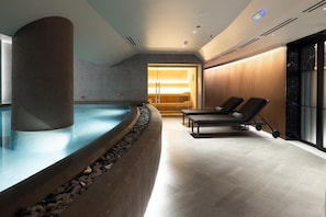 Un espace bien-être comprenant un jacuzzi, des chaises longues et un mur en bois.