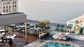 Zona de piscina en la azotea con mobiliario exterior y vistas al mar.