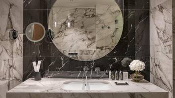 A modern bathroom with a marble vanity, a large mirror, and a glass shower enclosure.