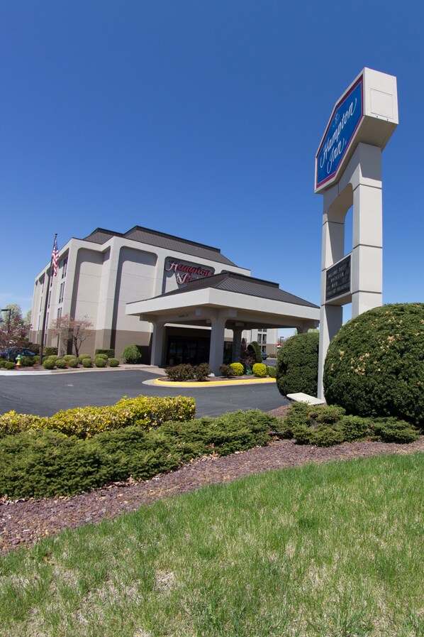 A Hampton Inn hotel with a clear blue sky, a parking lot, and well-maintained landscaping. - Hampton Inn Winchester-University/Mall Area (Winchester)