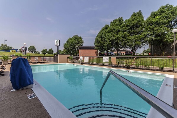 Relax by the pool surrounded by lush surroundings and a covered seating area.