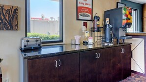 A hotel reception area with a window, a framed sign, a coffee machine, a toaster, and a counter.