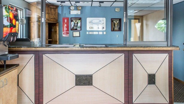 A hotel reception area with a counter, framed awards, and a blue wall.