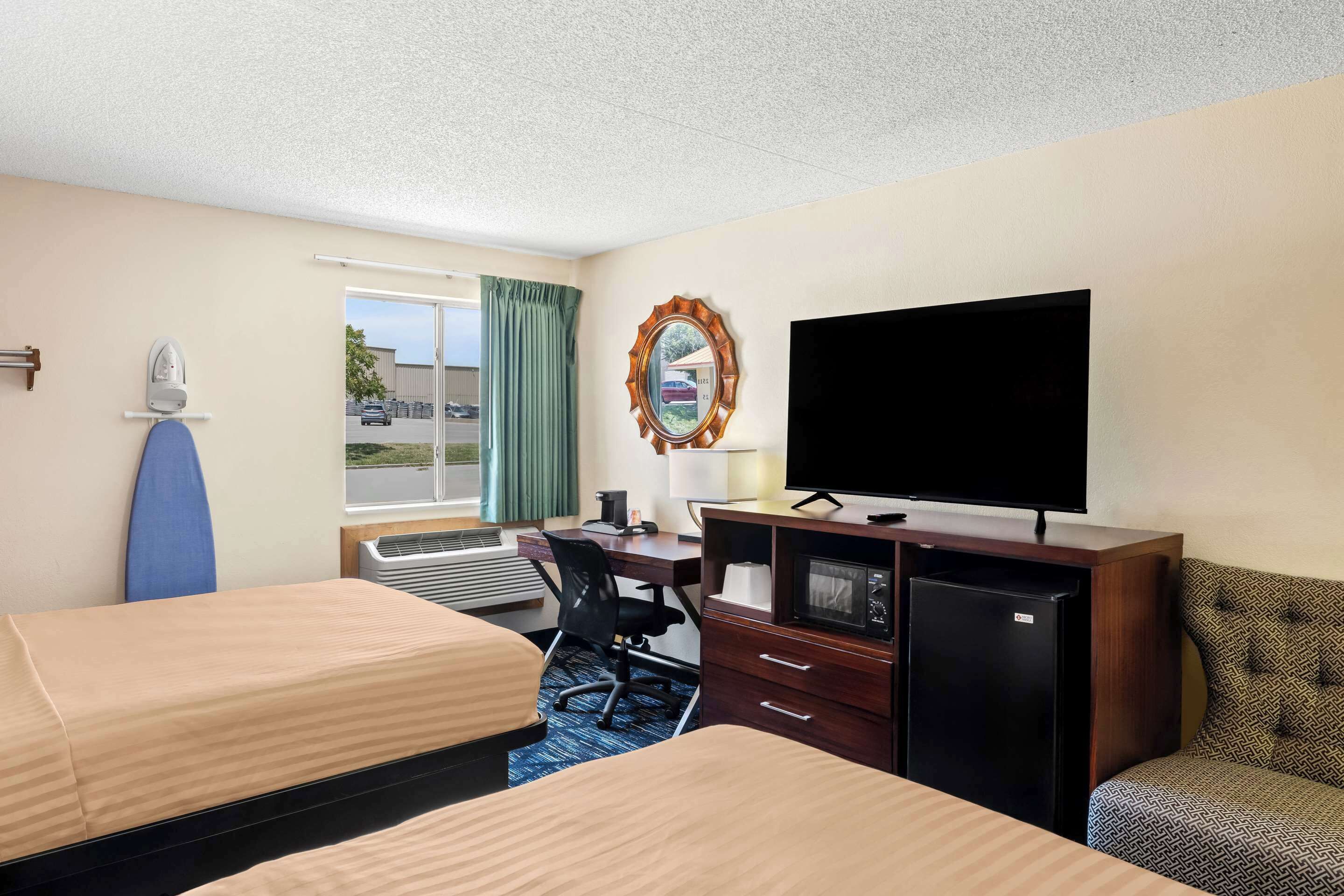 Een hotelkamer met twee bedden, een bureau, een televisie, een magnetron en een kleine koelkast.