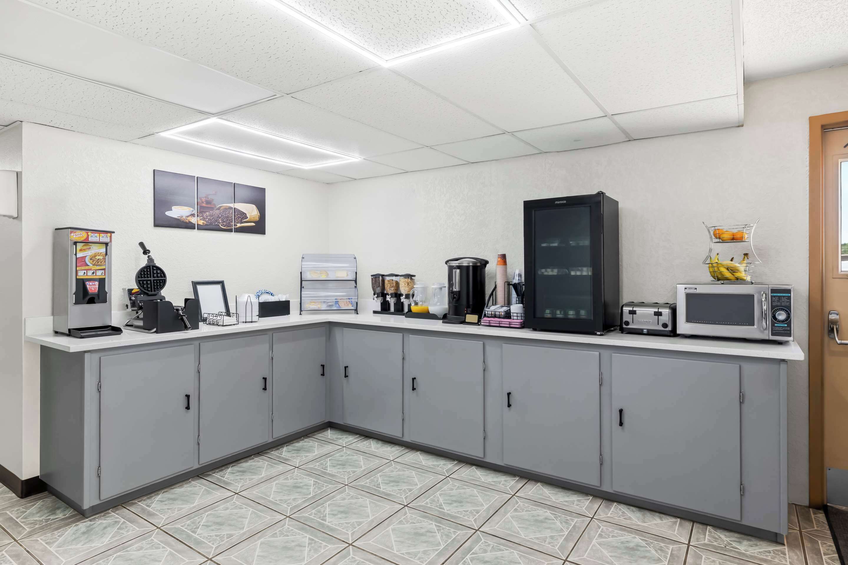 A kitchen with grey cabinets, a coffee machine, a microwave, and a refrigerator.