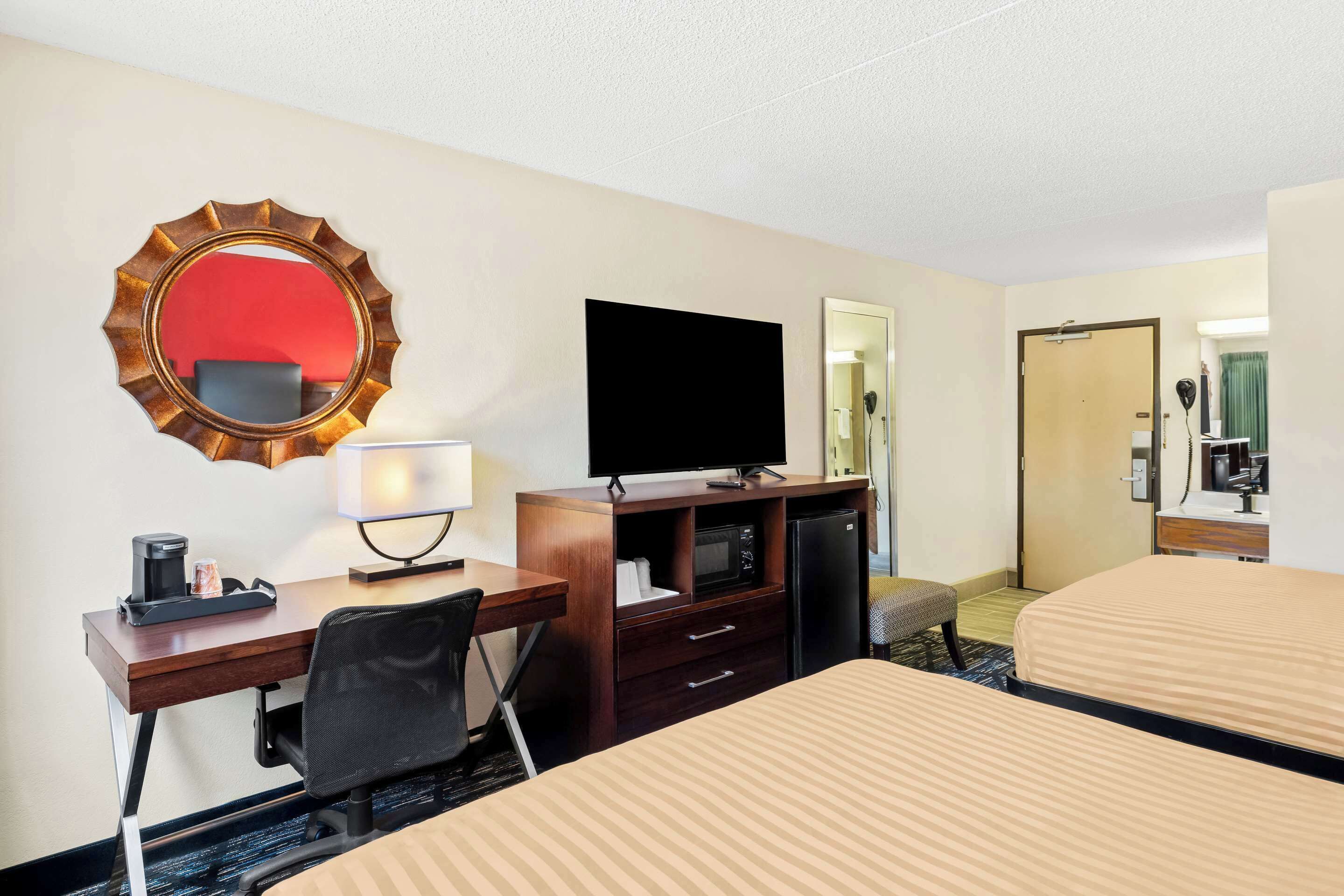 A hotel room with a desk, a television, a microwave, and a bed.