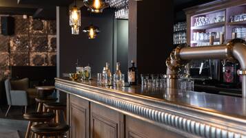 A bar area with stools, bottles, glasses, and a bar counter.