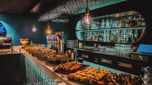 A bar area with a variety of food items, a bar counter, and shelves of liquor bottles. - Hôtel Fahrenheit Seven Val Thorens (Les Belleville)