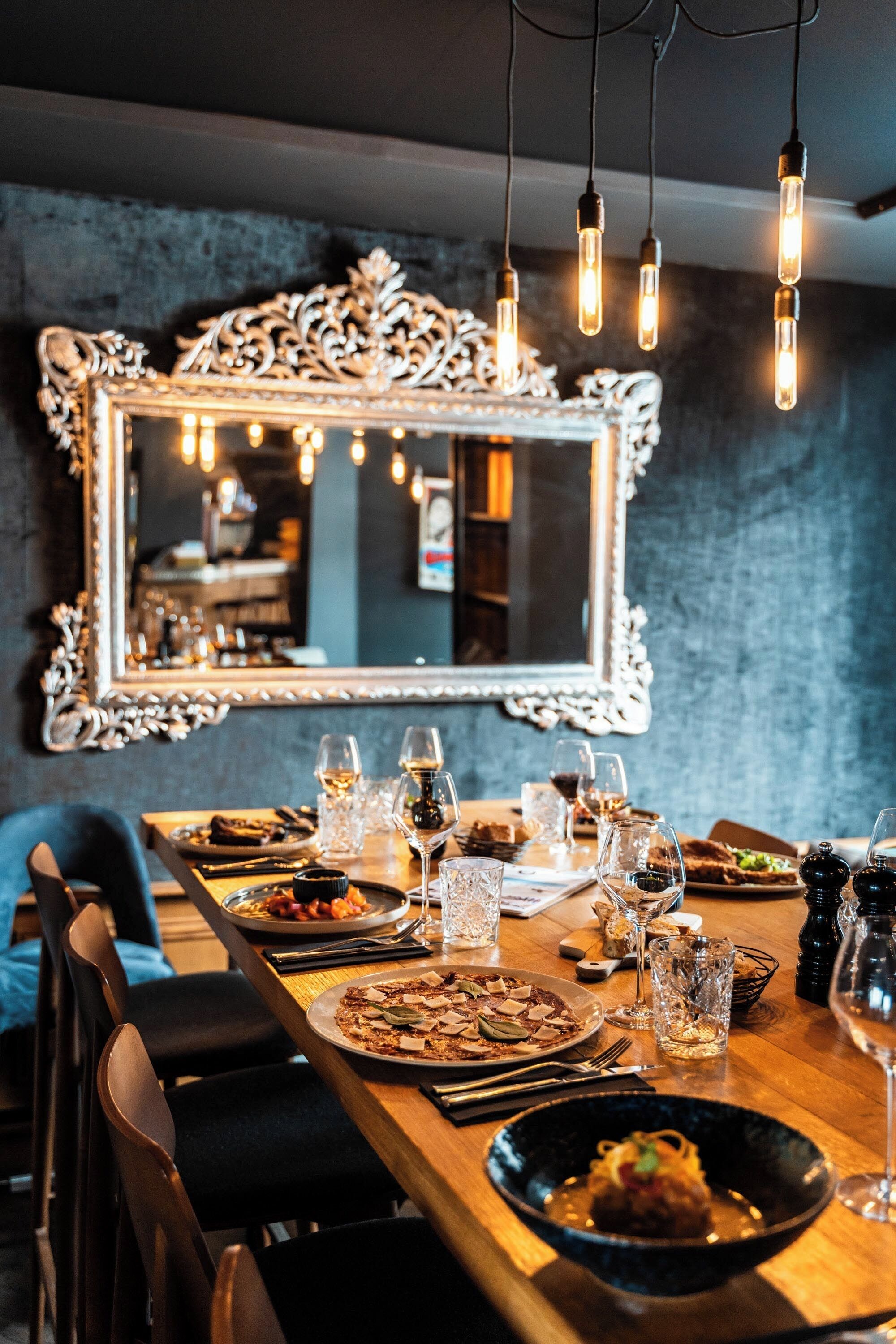 A dining table set with various dishes, glasses, and a mirror with an ornate frame.