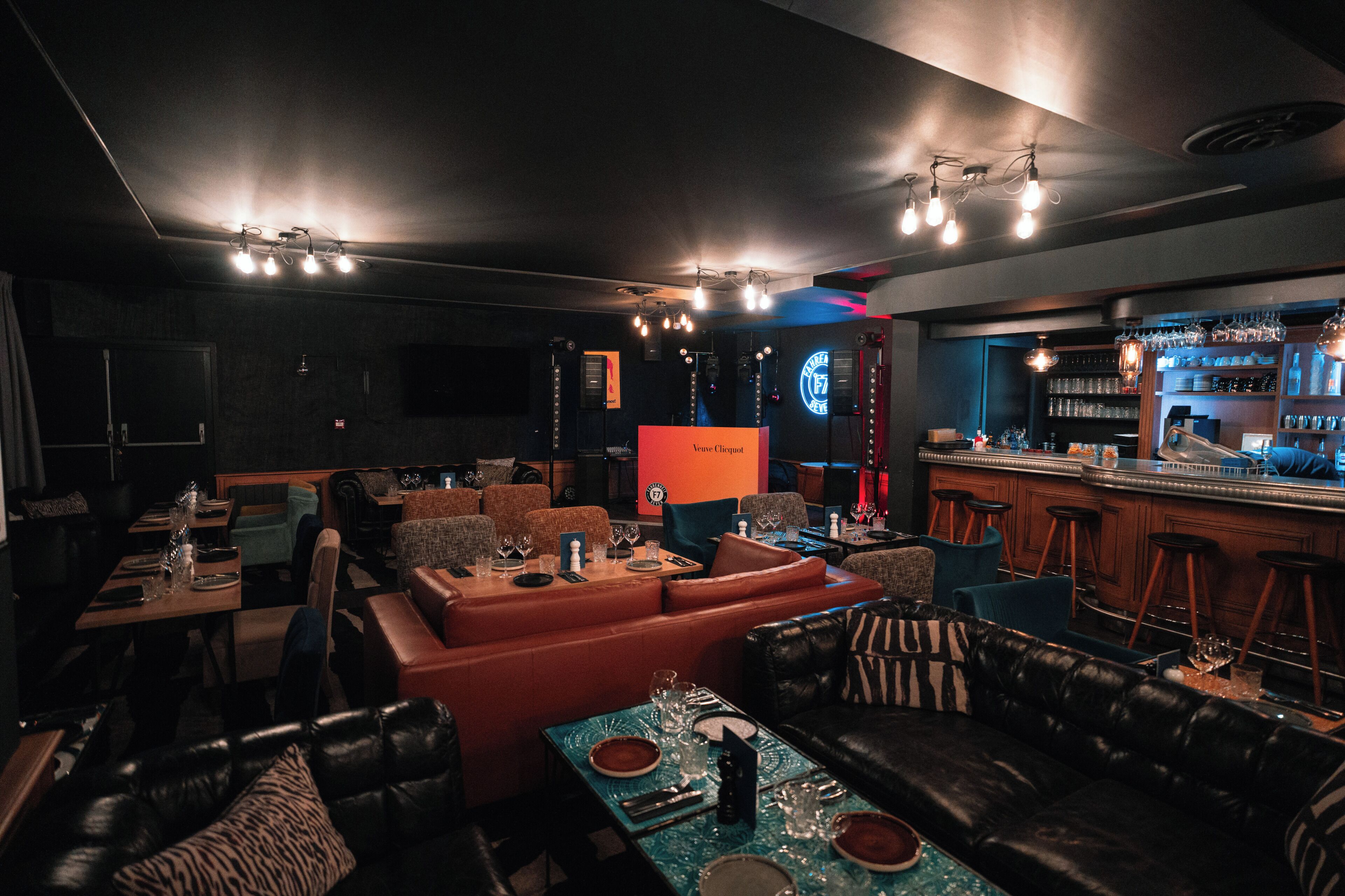 Un espace bar avec des tabourets, un comptoir et un coin salon avec des canapés et des tables.