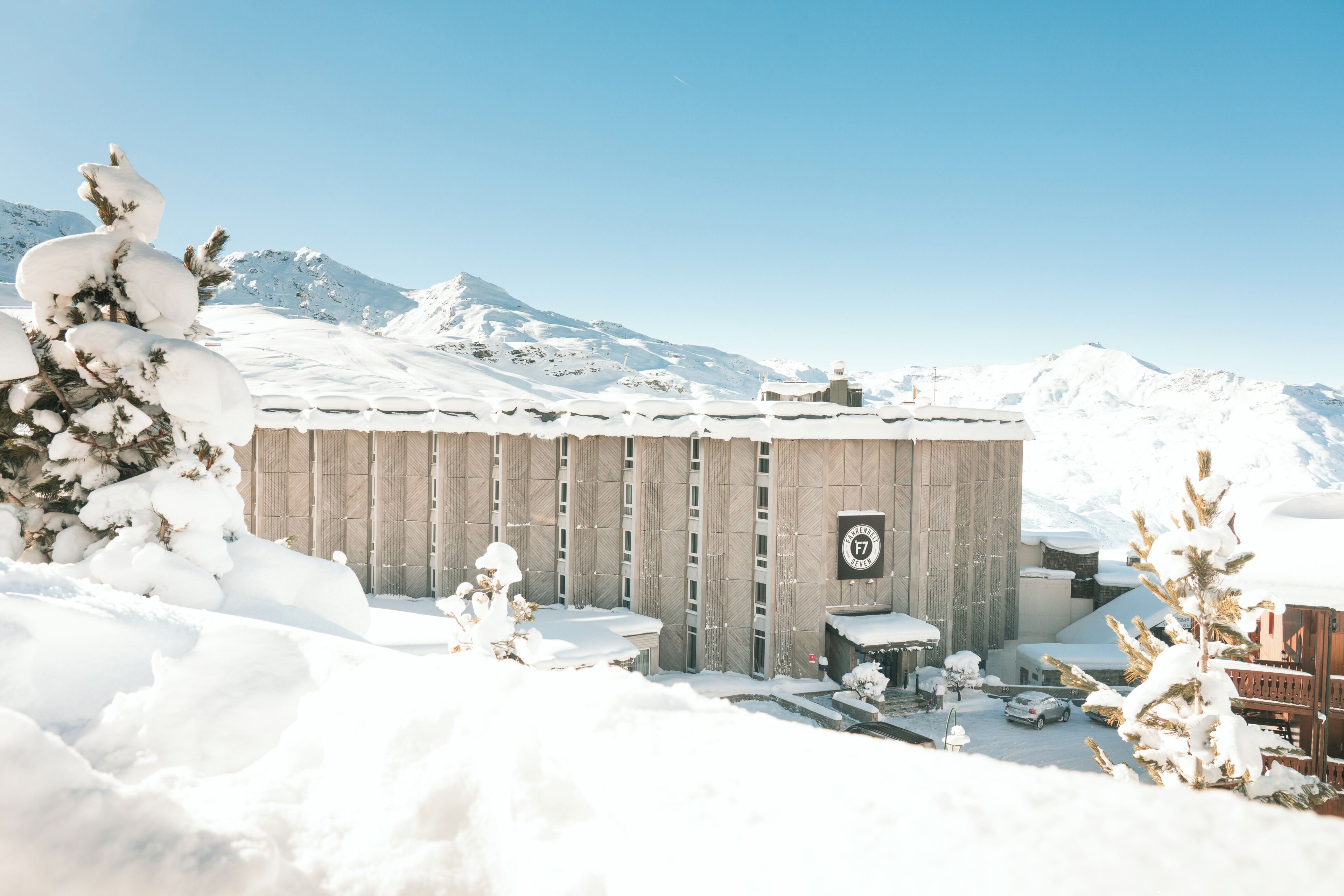 A snow-covered building with a clear sky and mountains in the background.