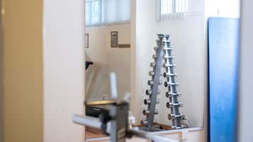 Un gimnasio con equipo de ejercicio, un espejo y una ventana con persianas.