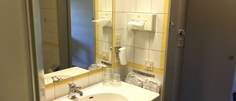 Un baño con un lavabo blanco, un espejo y un perchero para toallas.