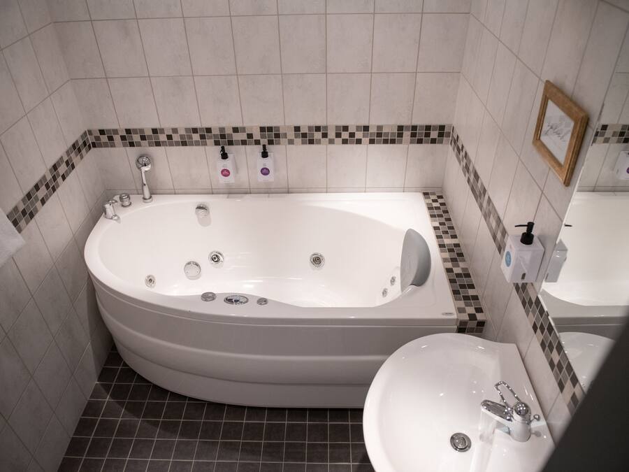 Un baño con una bañera grande, un lavabo y un espejo.