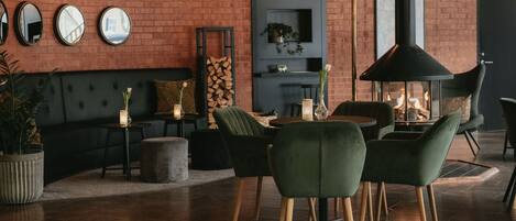 A modern interior with a brick wall, a sofa, a dining table with chairs, and a fireplace.