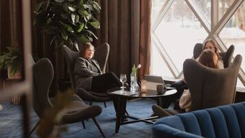 A room with a large window, a potted plant, and a table with a laptop and a glass of water.