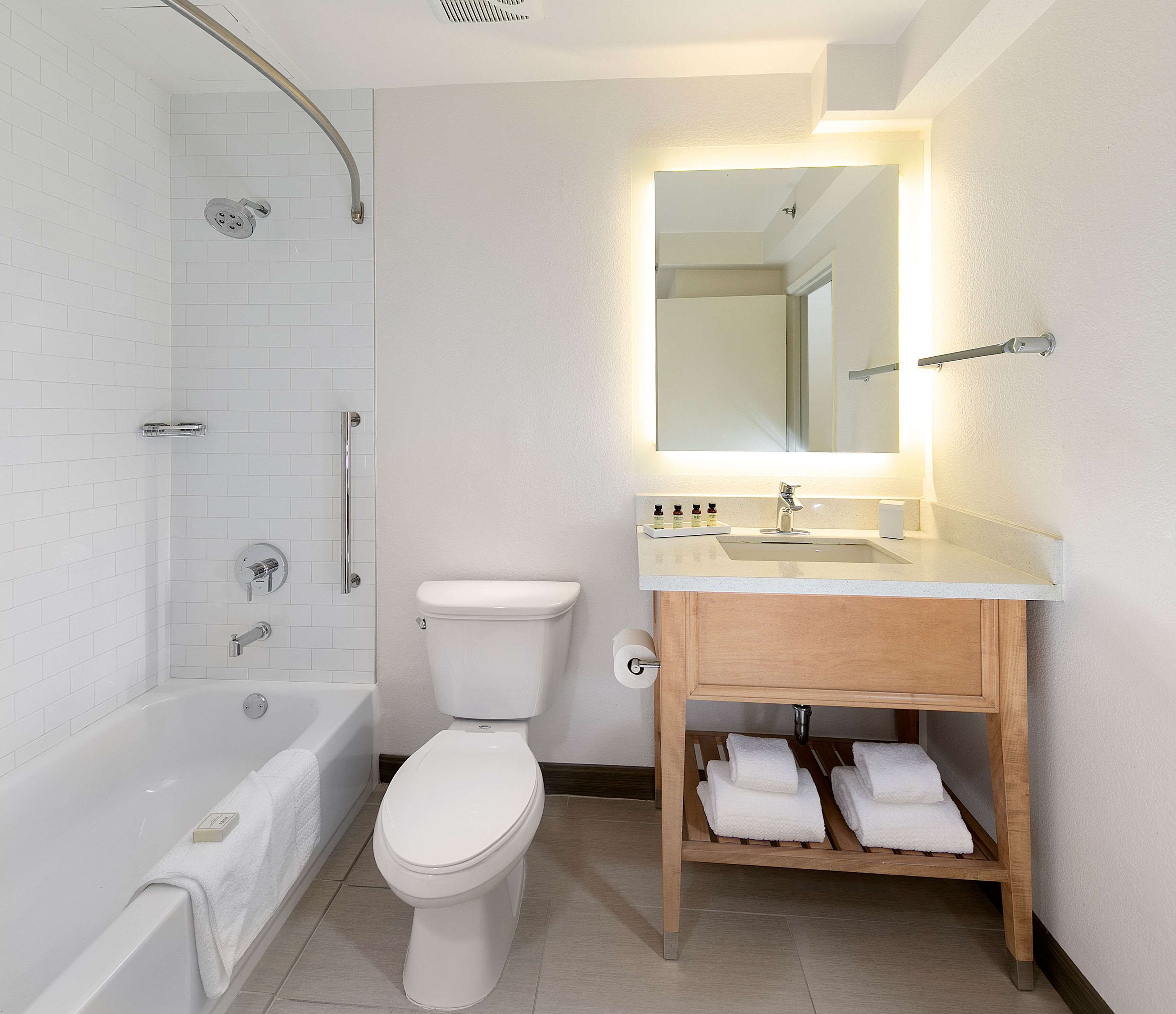 A modern bathroom with a bathtub, toilet, and vanity.