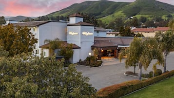A hotel with a prominent 'Wayfaver' sign, surrounded by lush greenery and hills in the background.
