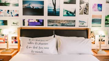 Ett hotellrum med en säng, två sängbord och en vägg som är dekorerad med olika fotografier.