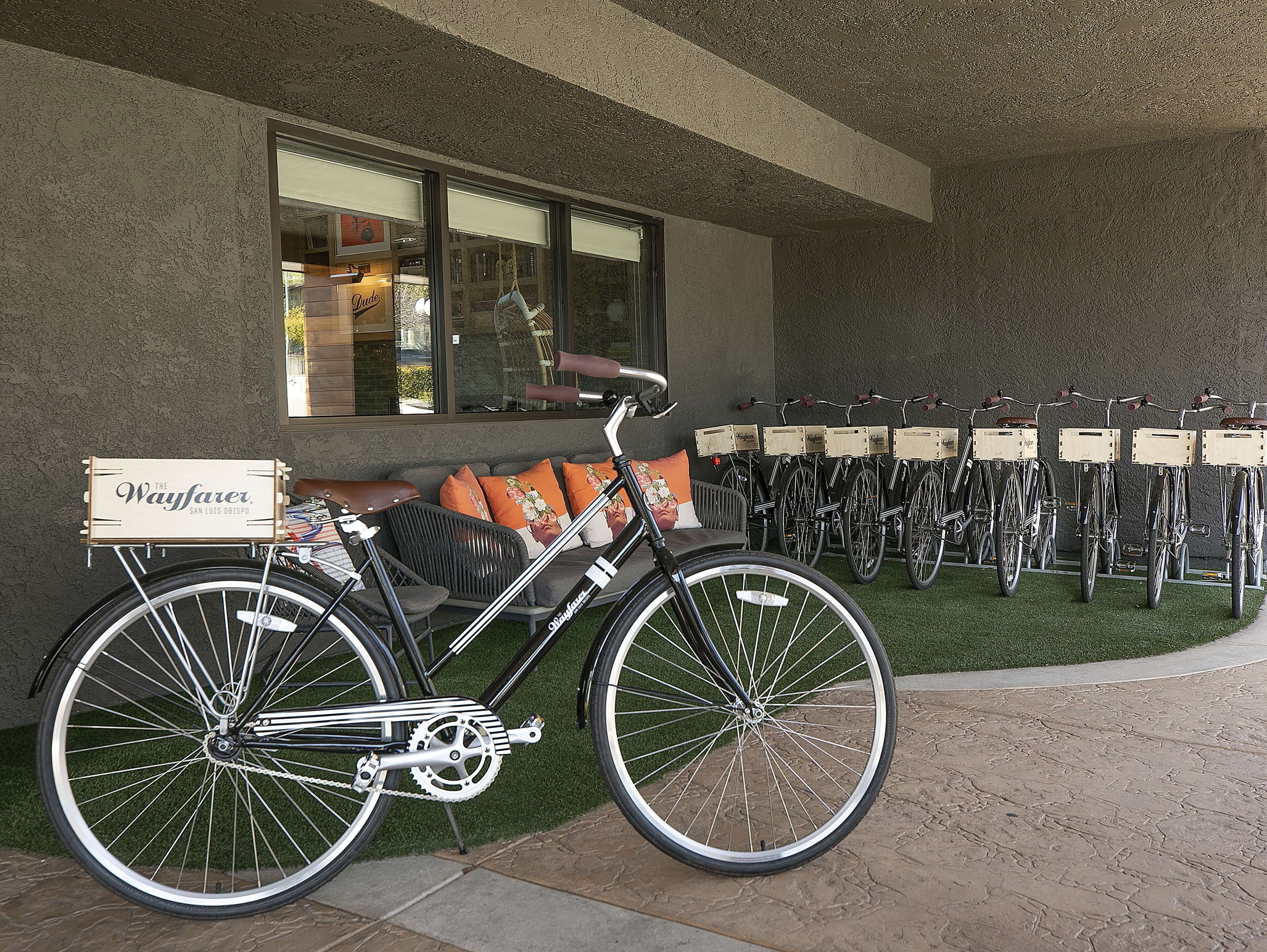 Un vélo équipé d’une caisse de livraison est garé devant un immeuble, où l’on peut voir une rangée de vélos.