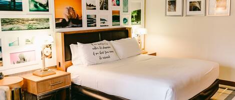 A neatly arranged bedroom with a bed, bedside tables, and a wall decorated with various framed pictures.