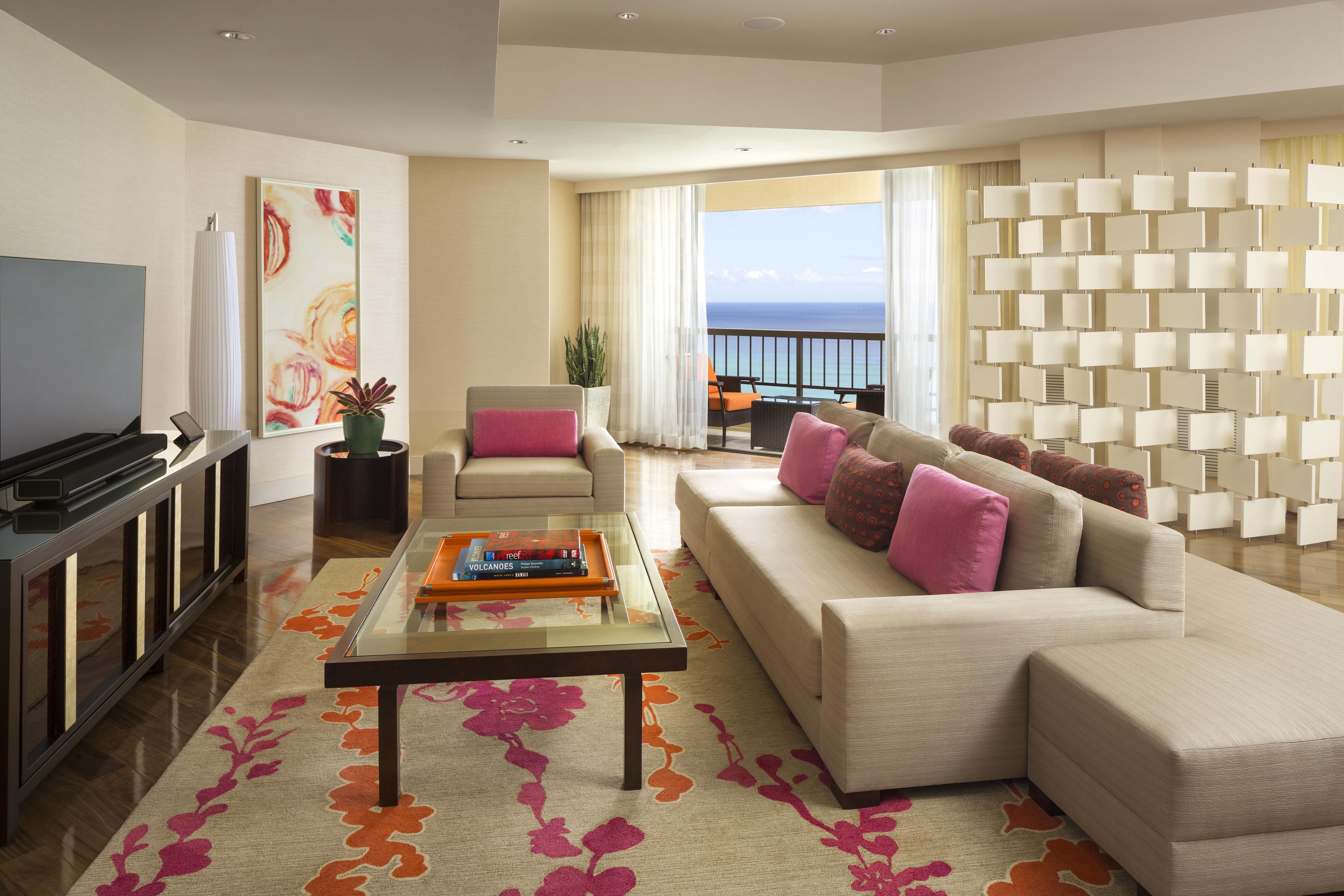 A modern living room with a sofa, coffee table, TV, and a balcony with a view.