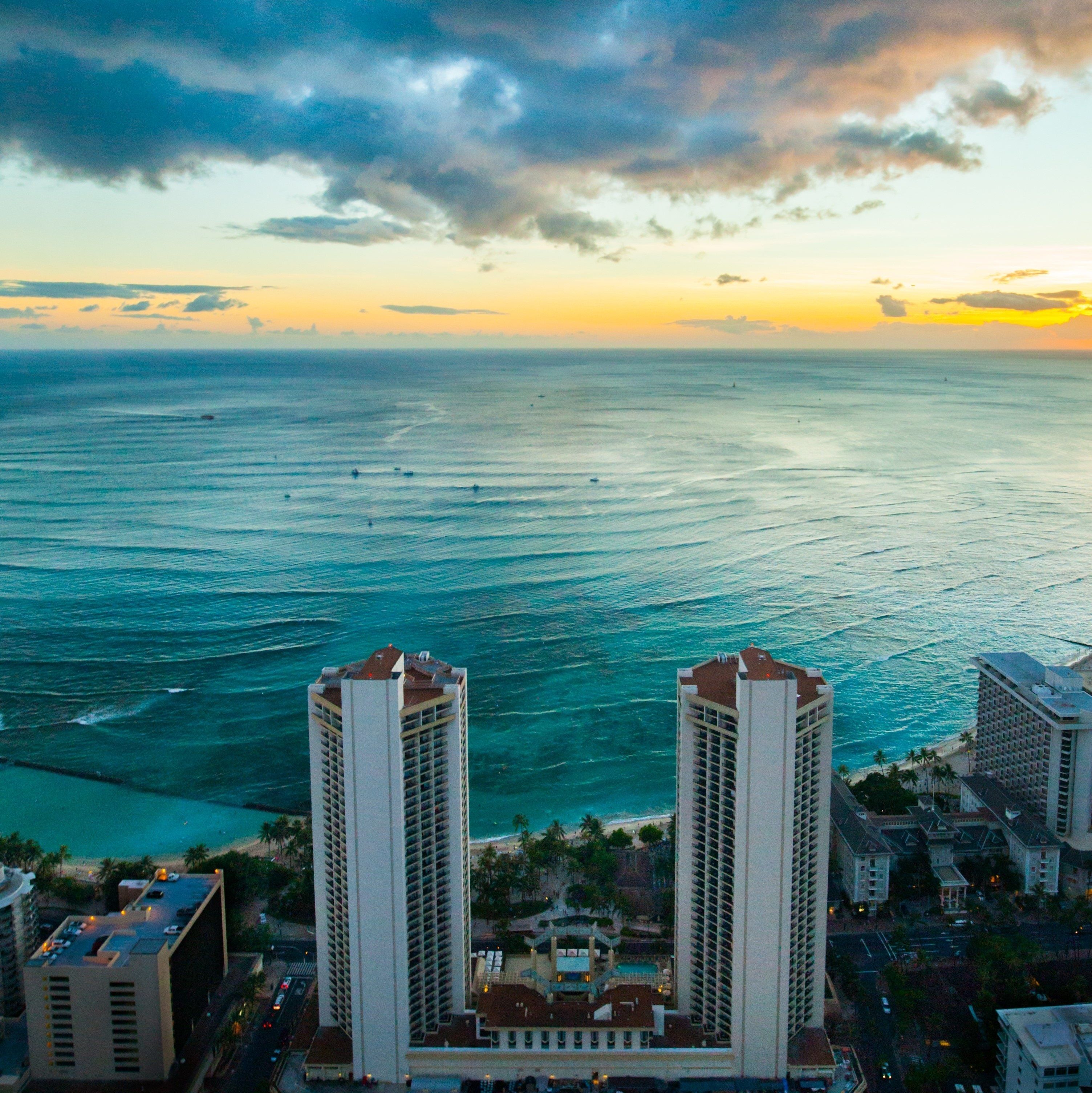 A high-rise hotel with a view of the ocean and sunset.