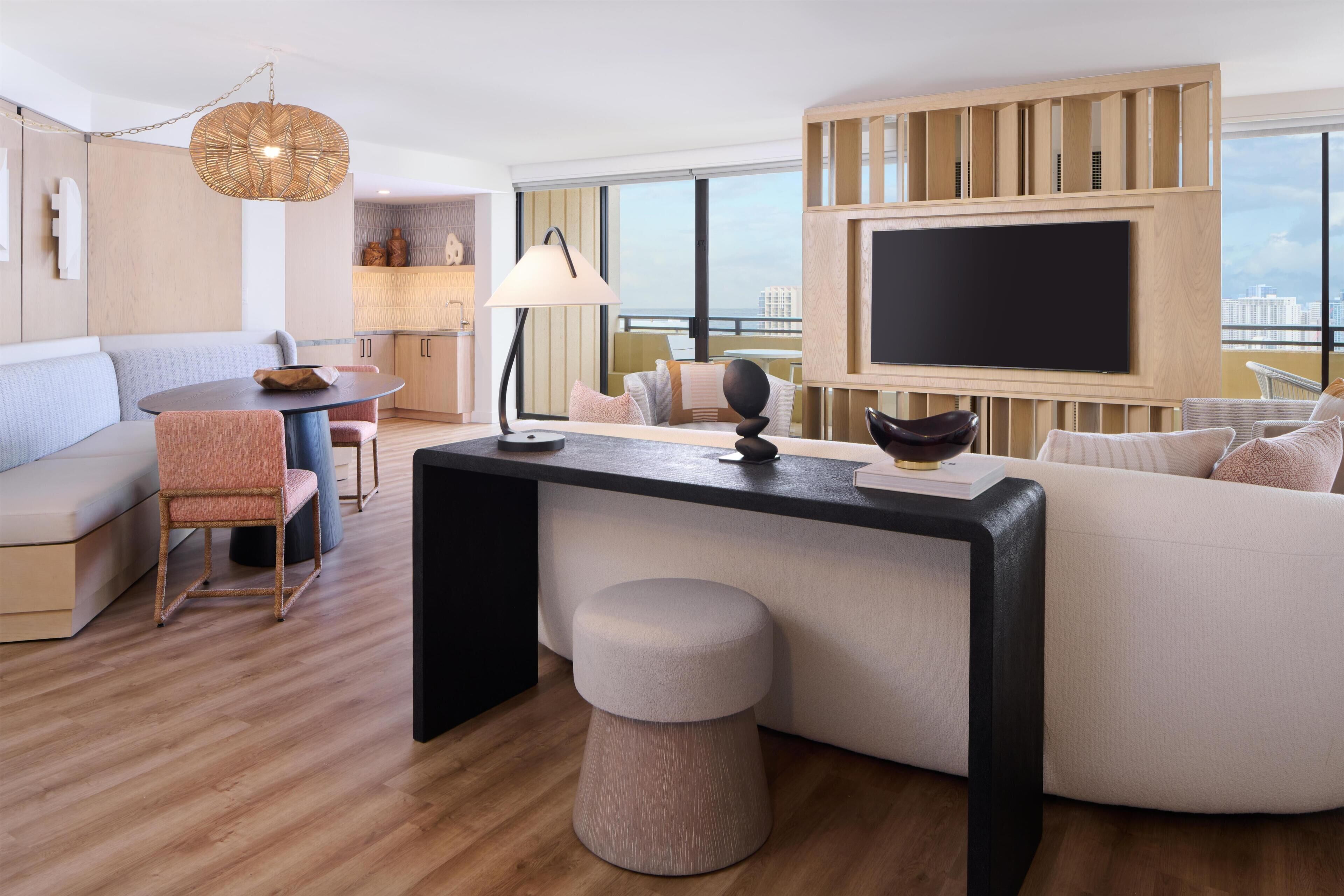 A modern living room with a sofa, a round table, a TV, and a city view.