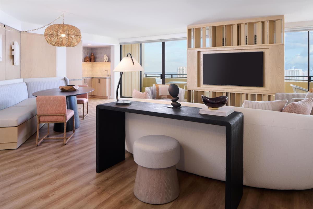 A modern living room with a sofa, a round table, a TV, and a city view.