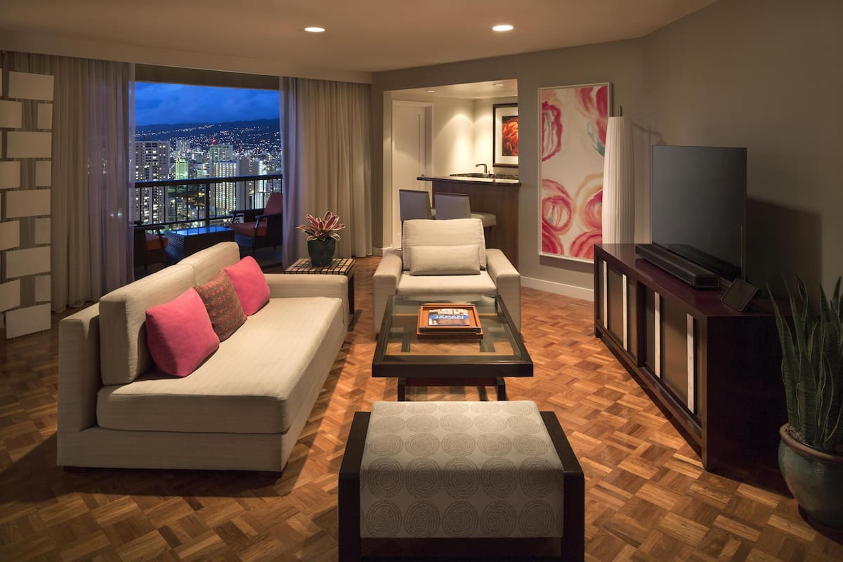 A modern living room with a sofa, armchairs, a coffee table, and a TV.