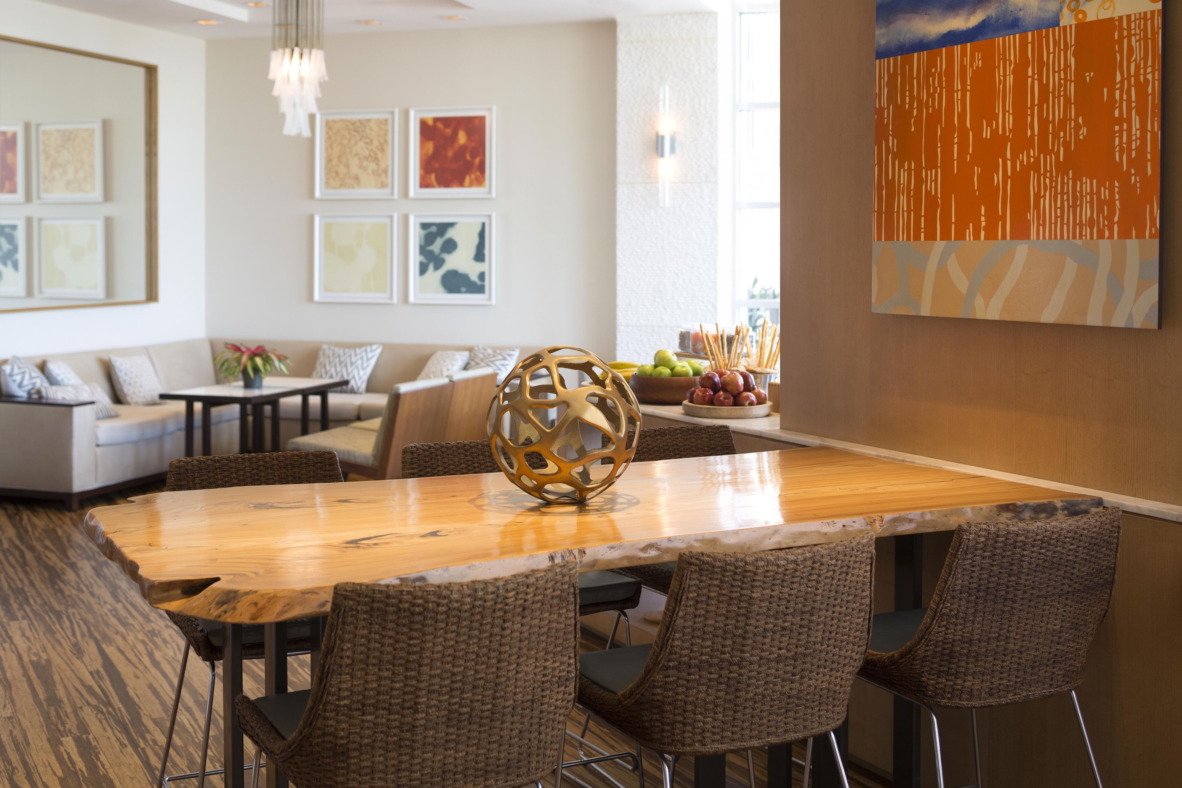 Un coin repas avec une table en bois, des chaises en osier et un élément décoratif au centre.
