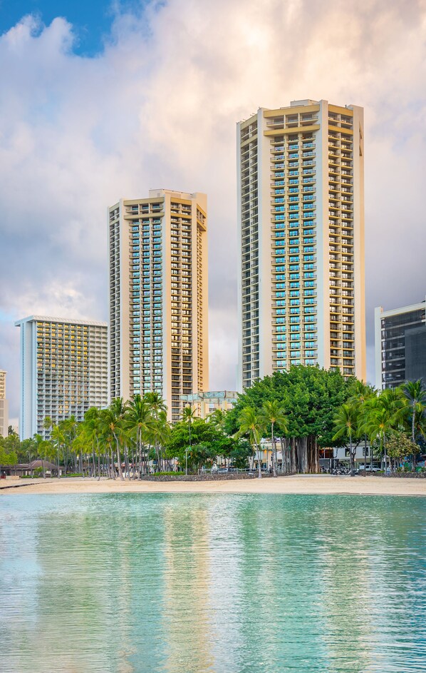 A high-rise hotel with multiple floors, a beach in the foreground, and palm trees. - Hyatt Regency Waikiki Beach Resort & Spa (Honolulu)
