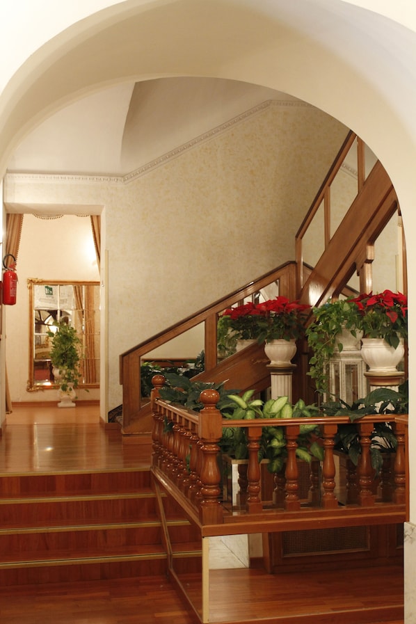 A grand staircase with wooden balusters and a handrail, leading to an upper floor. - Pace Helvezia (Rome)